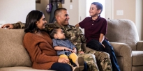 Soldier sitting on a couch with his family. 