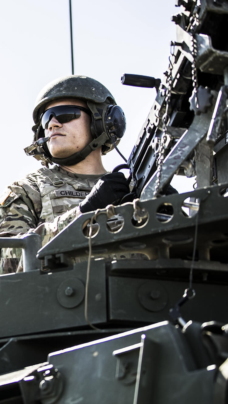 Army Soldier manning a piece of heavy artillery in the field.