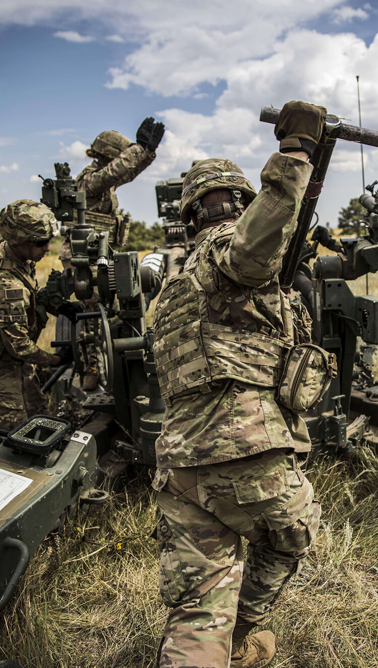 Two Army Soldiers repairing equipment in the field.