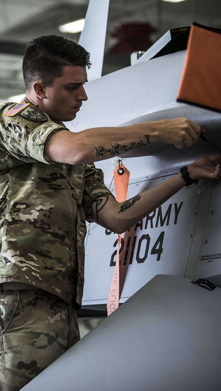 Army mechanic performing repairs on aircraft.