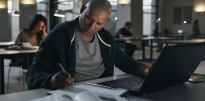 SSG Oscar Dominguez wearing civilian clothing sitting inside a library studying with a laptop.