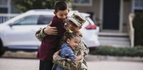 SSG Rodriguez wearing OCP kneeling and hugging his children.